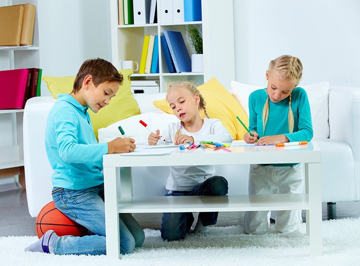 Portrait of three children drawing at home